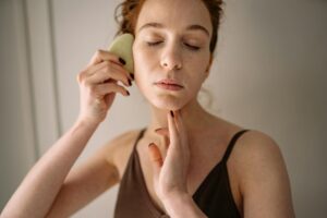 close up photo of woman using gua sha